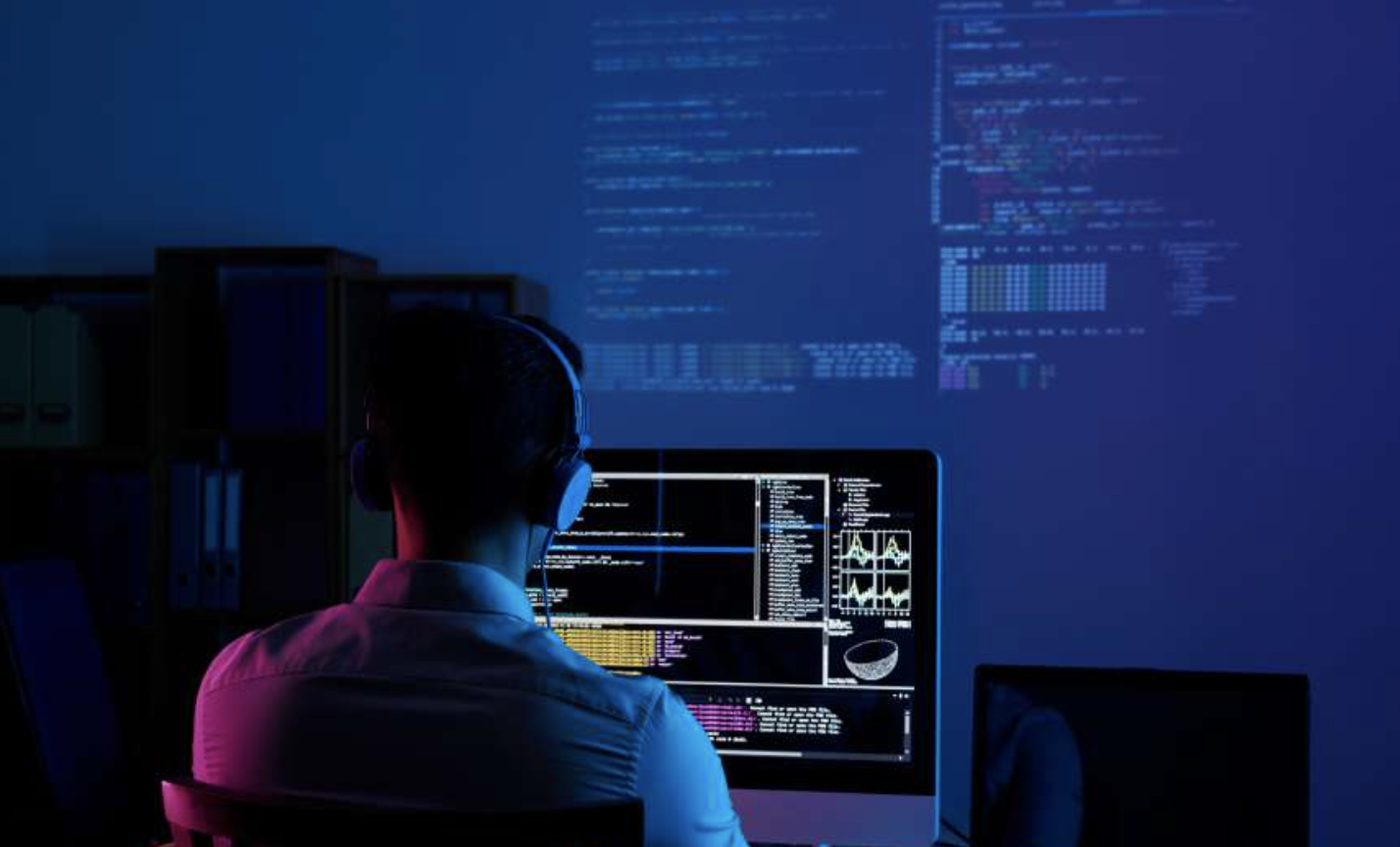 Programador construyendo tu aplicación frente a una pantalla con código